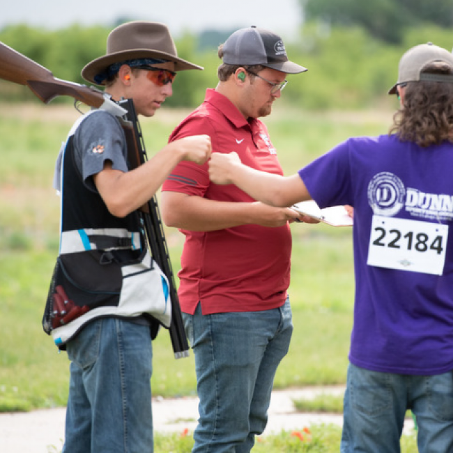 2 kids fist bump at a shooting competition