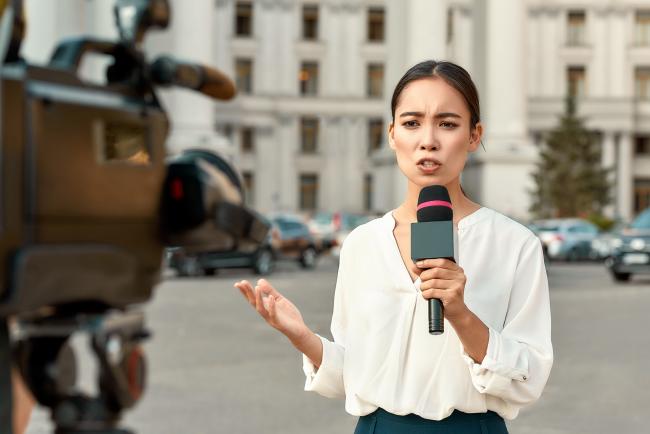 reporter on site speaking into camera holding microphone