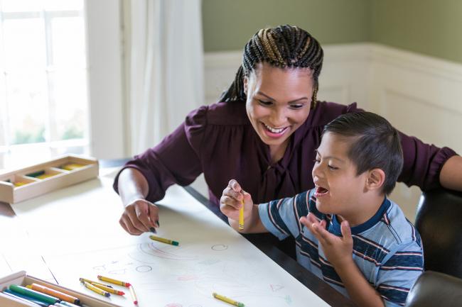 Teacher and boy draw with crayons