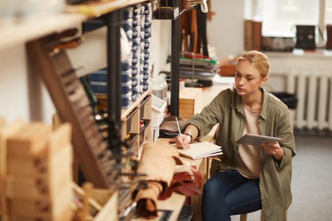 Woman in work studio writing on notebook