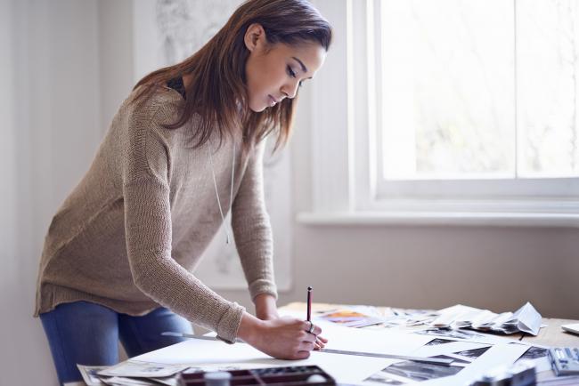 woman standing over her desk working on scrapbook