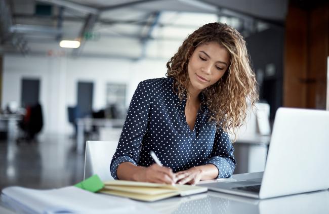 woman at work writing notes in a journal