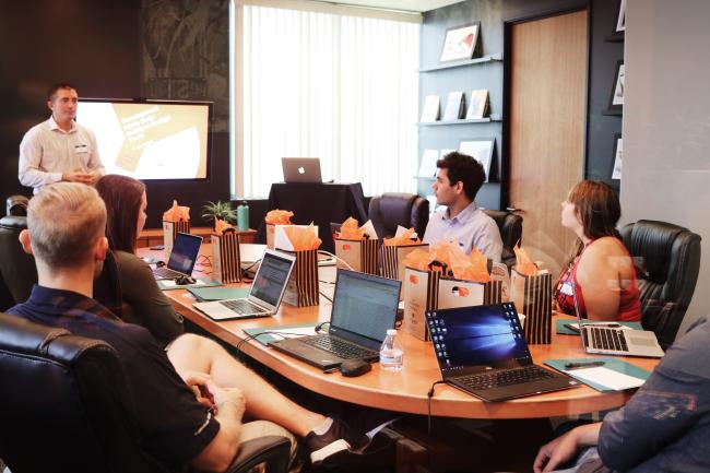 man leading a group gathered around a conference table