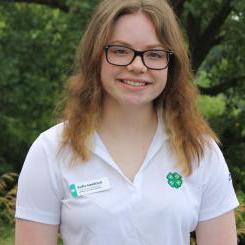 Girl with wavy brown hair and glasses in white shirt